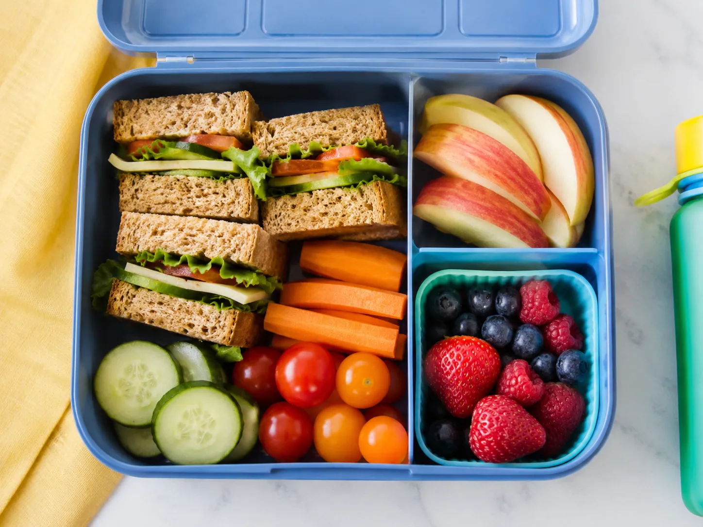 Kleurrijke broodtrommel met volkoren sandwiches, fruit en verse groenten voor een voedzame lunch op school.