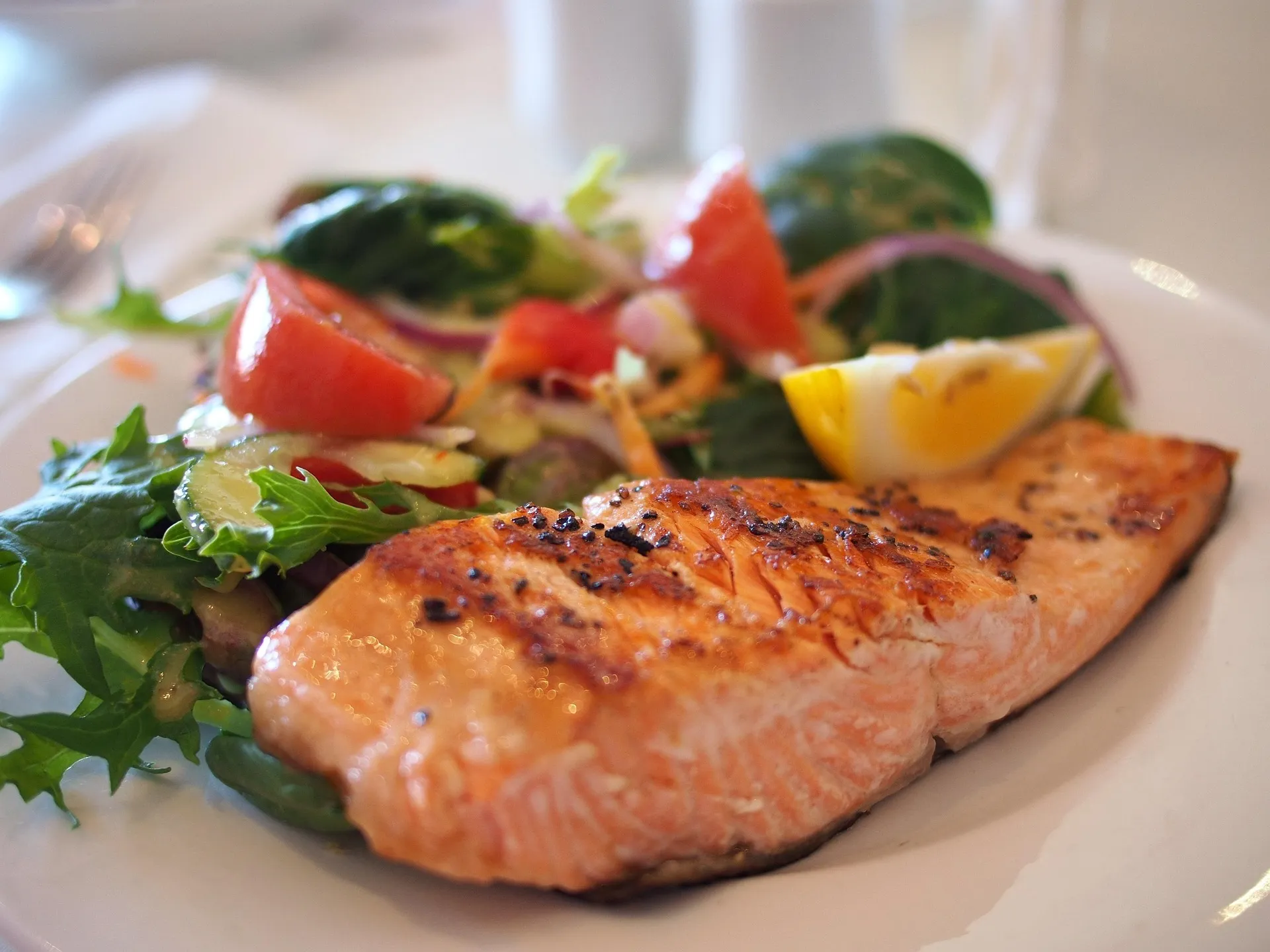Gegrilde zalm met frisse salade en citroen, ideaal als gezonde werklunch.