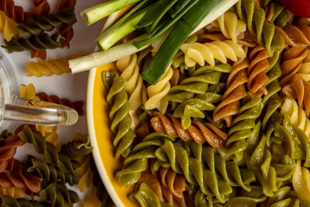 Kleurrijke pastasalade met lente-ui, makkelijk mee te nemen zonder koeling.